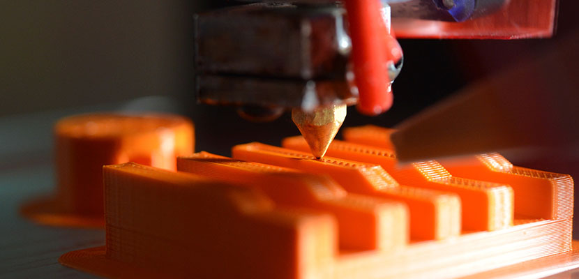 3D printer printing an orange object
